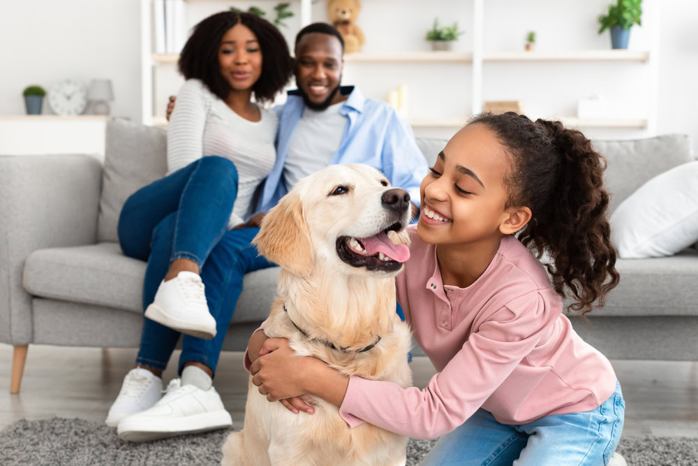 a kid hugging their pet dog with parents on the couch