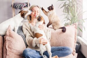 happy woman playing with her dogs and cat